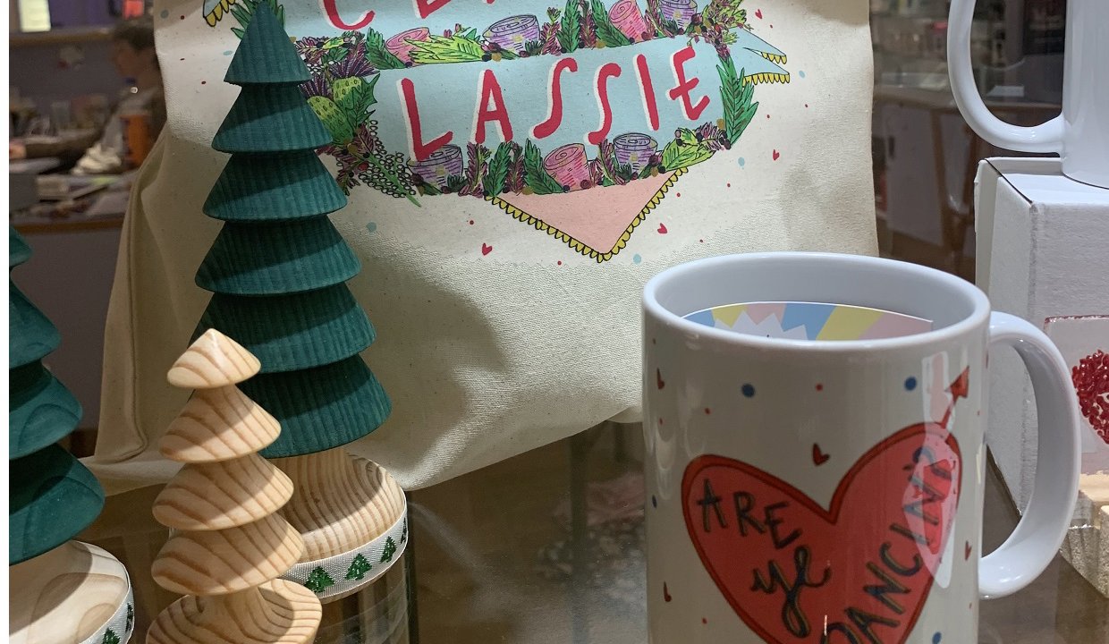 A tote bag with classy lassie and wrote on it inside a heard with wooden tree ornaments and a mug