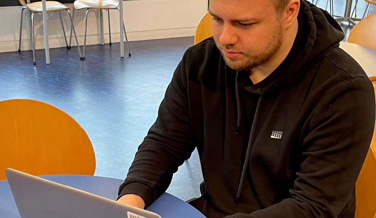Andrew Kerr, a man who was helped to find his perfect job by EDC social work team, sits at a table working on his laptop