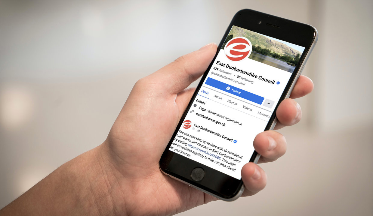 Hand holding a phone with the council's facebook page open