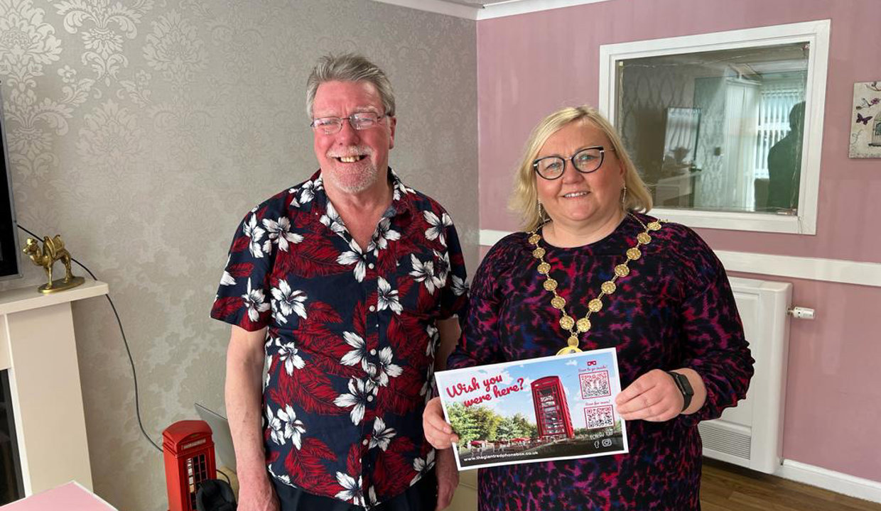 Provost Renwick holding poster with big red phone box on it